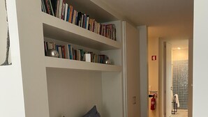 Une chambre à coucher avec un lit, une bibliothèque et une salle de bain visible à travers une porte ouverte.