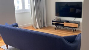 Un salon moderne avec un canapé bleu, un téléviseur à écran plat et un plancher en bois.