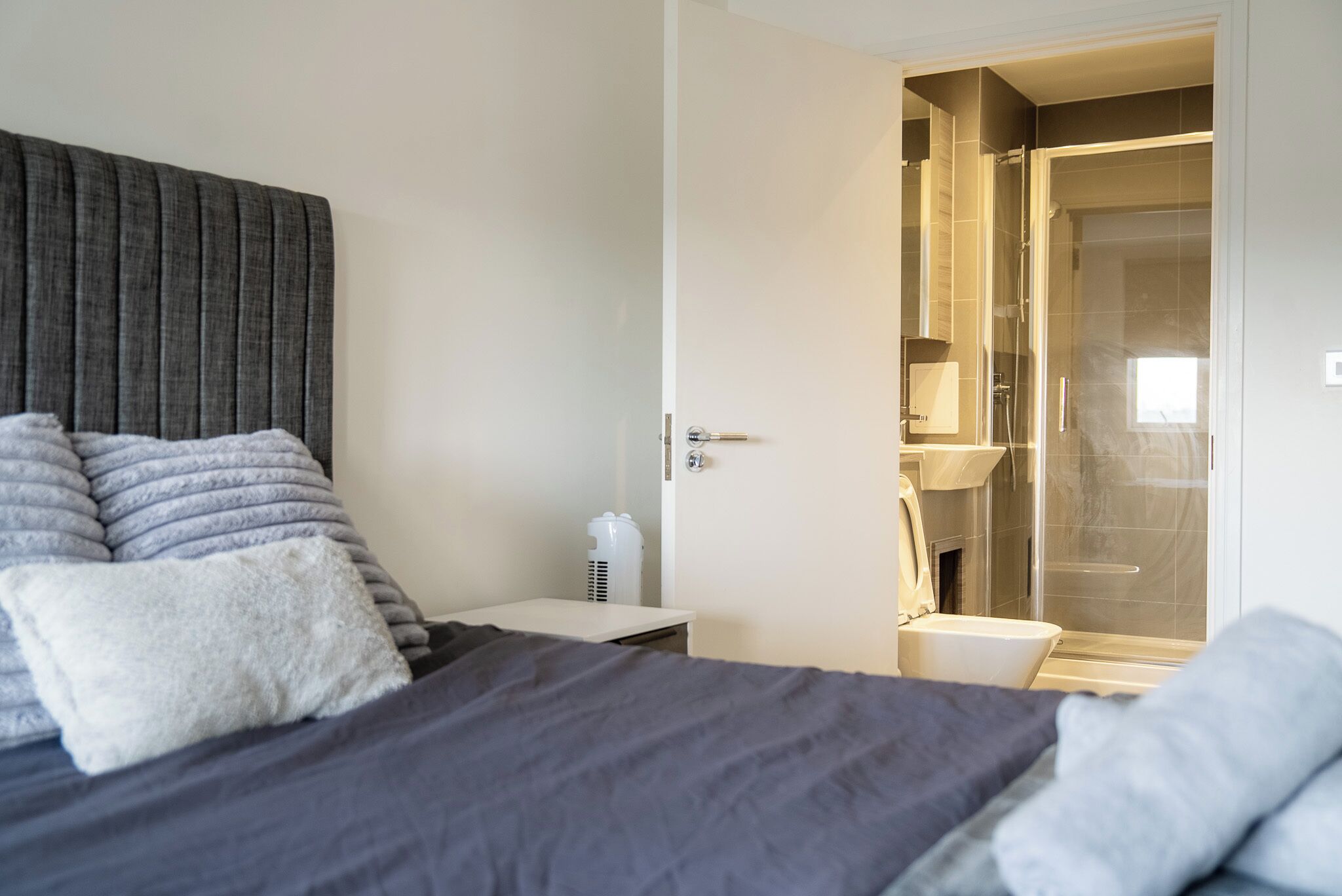 Une chambre à coucher comprenant un lit, une table de chevet, une commode et une salle de bain avec douche et toilettes.
