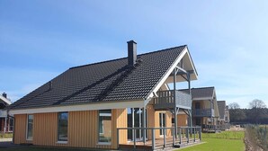 A modern two-story house with a balcony, large windows, and a well-maintained lawn. - Ferienhaus im Skandinavischen Stil (Mirow)