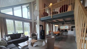 A spacious living area with a sofa, chairs, a dining table, and a kitchen in the background. - Ferienhaus im Skandinavischen Stil (Mirow)