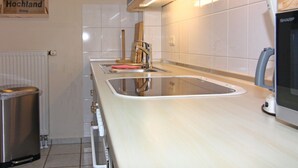 A kitchen with a stainless steel sink, a wooden cutting board, and a sign for 'CAFÉS DO BRASIL'. - Holiday Complex Orther Reede - Fehmarn (Fehmarn)