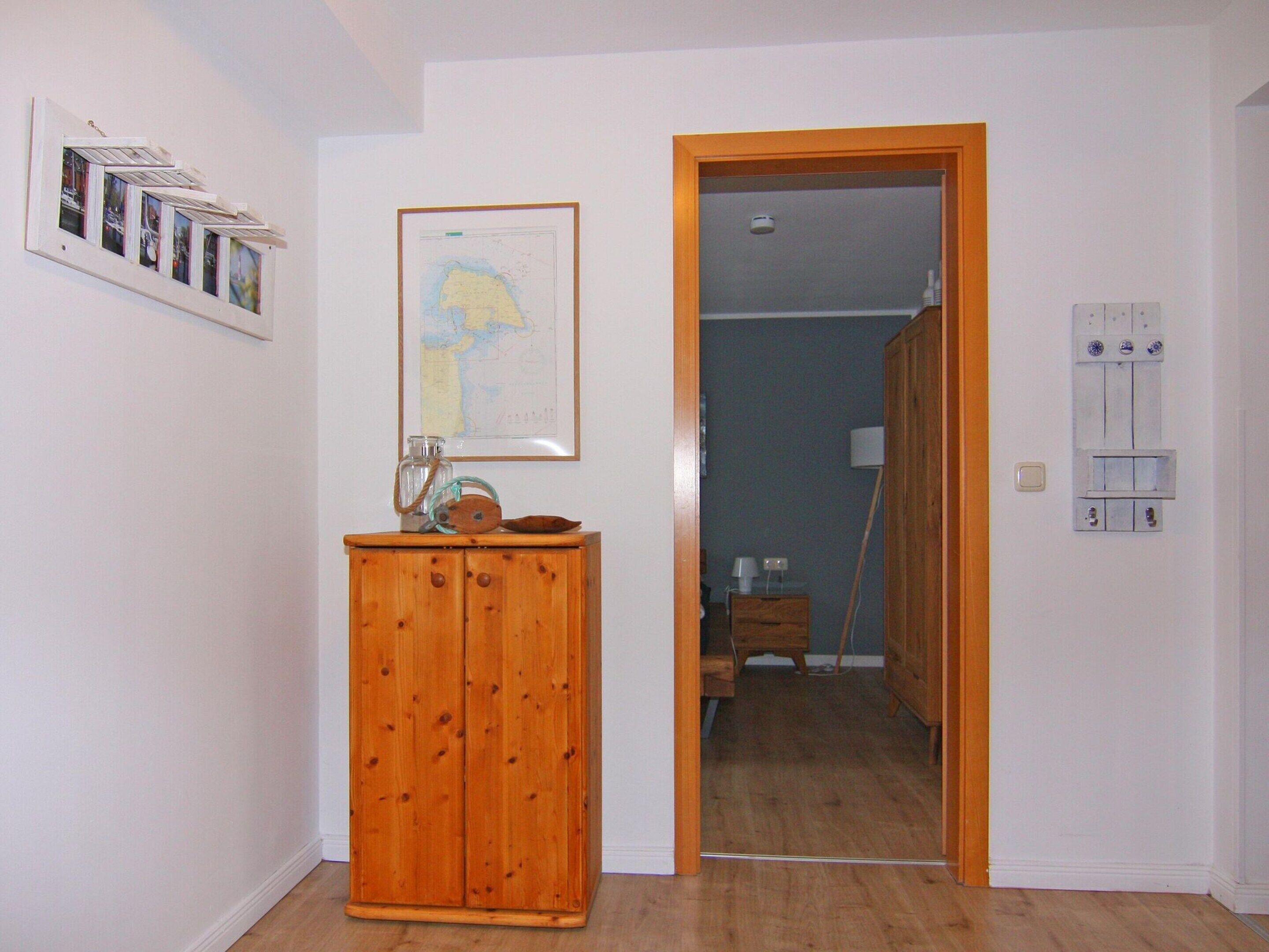 A room with a wooden cabinet, a map on the wall, and a door leading to another room.