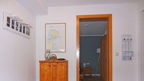 A room with a wooden cabinet, a map on the wall, and a door leading to another room. - Holiday Complex Orther Reede - Fehmarn (Fehmarn)