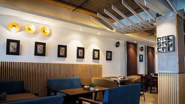 A modern restaurant interior with wooden paneling, blue upholstered seating, and wall-mounted artwork.