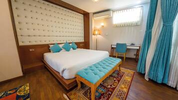 A hotel room with a large bed, a desk, a chair, and a window with curtains.