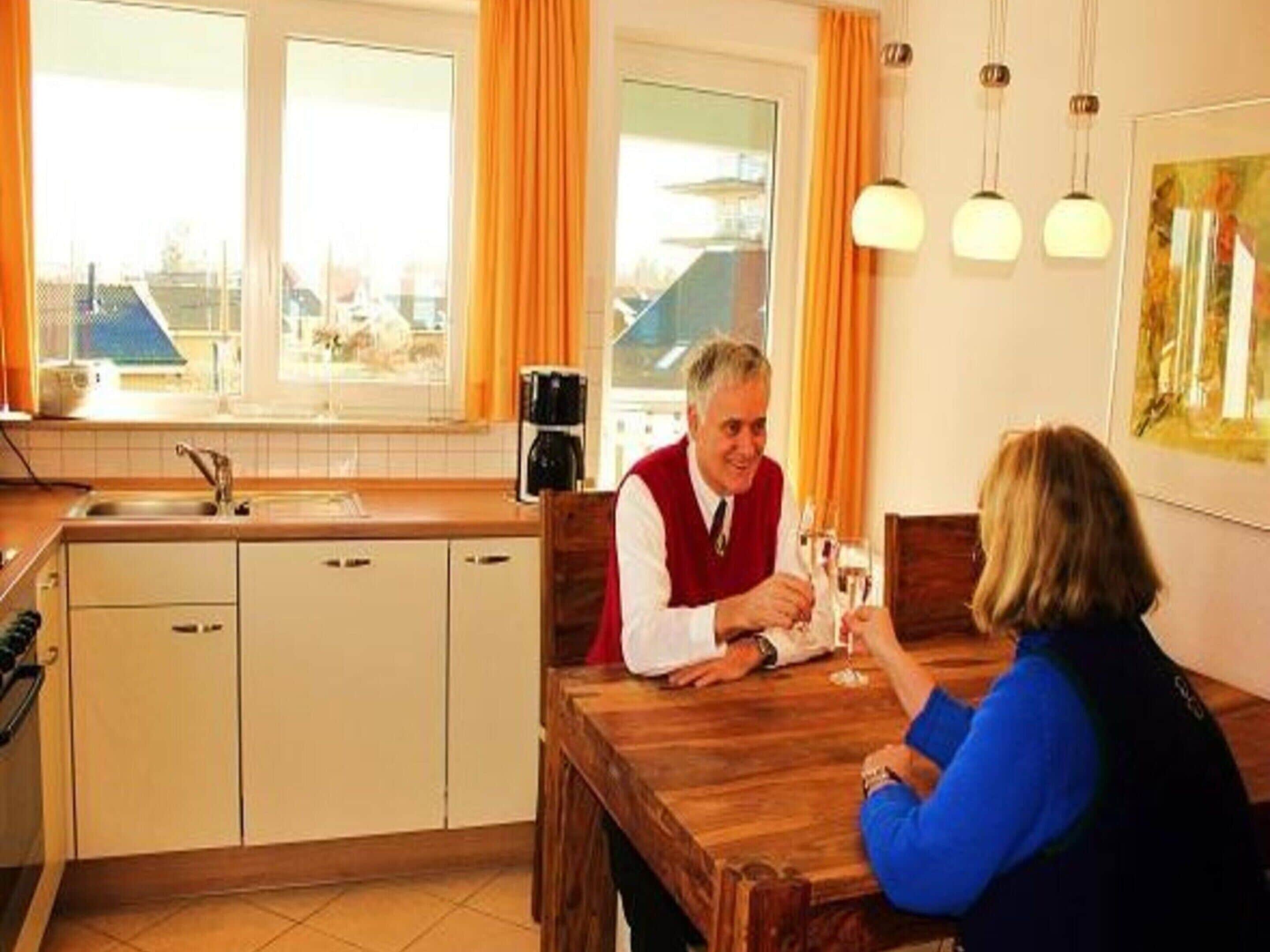 A modern kitchen with white cabinets, a wooden dining table, and a coffee machine.