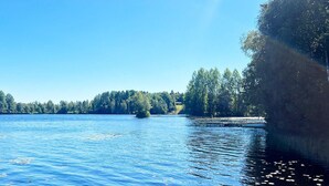 Um lago calmo com um cais e árvores ao fundo.