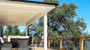 Varanda coberta ao ar livre com móveis de vime e vista para árvores.