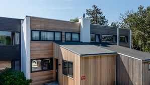 A modern two-story building with a flat roof, large windows, and a wooden facade. - Holiday Home Nieuwvliet Near Beach & Dunes (Nieuwvliet)