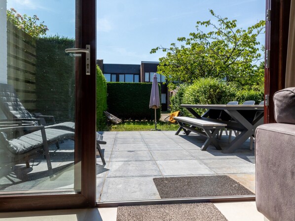 A patio with a table and chairs, a bench, and a glass door leading outside.