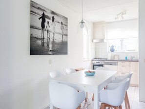 A modern kitchen with white cabinets, a large window, and a dining area with a white table and chairs. - Spacious Holiday Home With Sauna Near Beach (Wemeldinge)