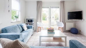 A living room with a sofa, a coffee table, a TV, and a bookshelf. - Spacious Holiday Home With Sauna Near Beach (Wemeldinge)