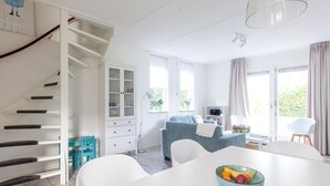 A modern kitchen with white cabinets, a dining table, and a staircase. - Spacious Holiday Home With Sauna Near Beach (Wemeldinge)