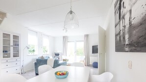 A modern living room with a dining area, a glass cabinet, a sofa, and a painting on the wall. - Spacious Holiday Home With Sauna Near Beach (Wemeldinge)