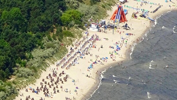An aerial view of a beach with numerous sun loungers and a large inflatable slide. - Ferienwohnung auf Usedom im Lepels Hof bis zu 5 P (Luetow)