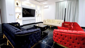 Un salon moderne avec un grand téléviseur à écran plat, un canapé et un fauteuil rouge.