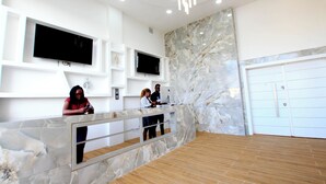 Un espace d’accueil avec des murs en marbre, un plancher en bois et un lustre moderne.
