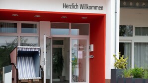 A building entrance with a red awning and a sign that reads "Herzlich Willkommen". - Elegant Eingerichtete Ferienwohnung (Mirow)