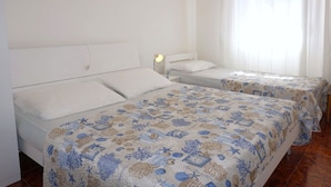 A hotel room with two single beds, a nightstand with a lamp, and three framed pictures on the wall.