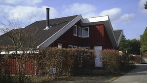 A red house with a sloped roof, a chimney, and a paved driveway. - Skandinavisches Ferienhaus in Mirow (Mirow)