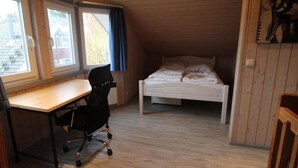 A room with a wooden ceiling, a bed, a desk, and a chair. - Skandinavisches Ferienhaus in Mirow (Mirow)