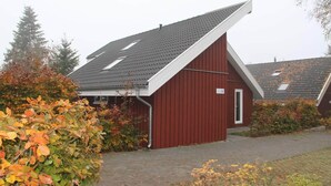 A red building with a sloped roof, a door, and a small window. - Ferienhaus im Skandinavischen Stil (Mirow)
