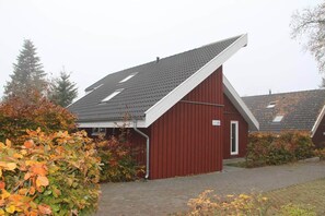 Ein rotes Gebäude mit geneigtem Dach, einer Tür und einem kleinen Fenster.