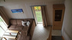 A cozy living room with a brown sofa, a small table, and a staircase leading to another level. - Ferienhaus im Skandinavischen Stil (Mirow)