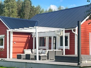 A red building with a covered patio area featuring outdoor seating. - 4 Star Holiday Home in Tavelsas (Tävelsås)