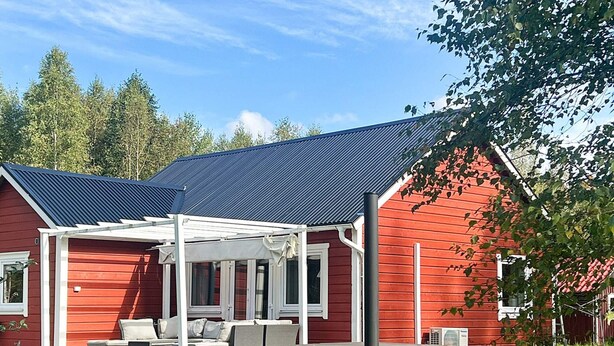Ein rotes Haus mit überdachter Terrasse und Solaranlage.
