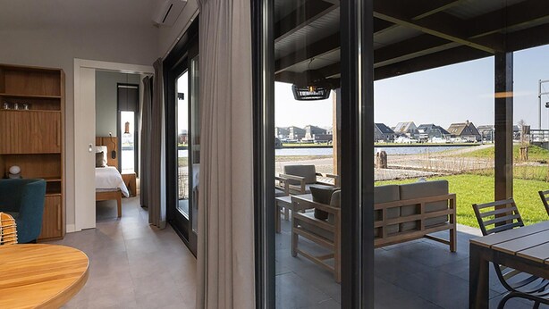 A modern interior with a large glass door leading to an outdoor seating area. - Waterfront Stay w/ Pets (Delfstrahuizen)