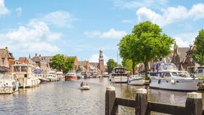 A canal with boats docked, wooden walkways, and traditional buildings along the water. - Waterfront Stay w/ Pets (Delfstrahuizen)
