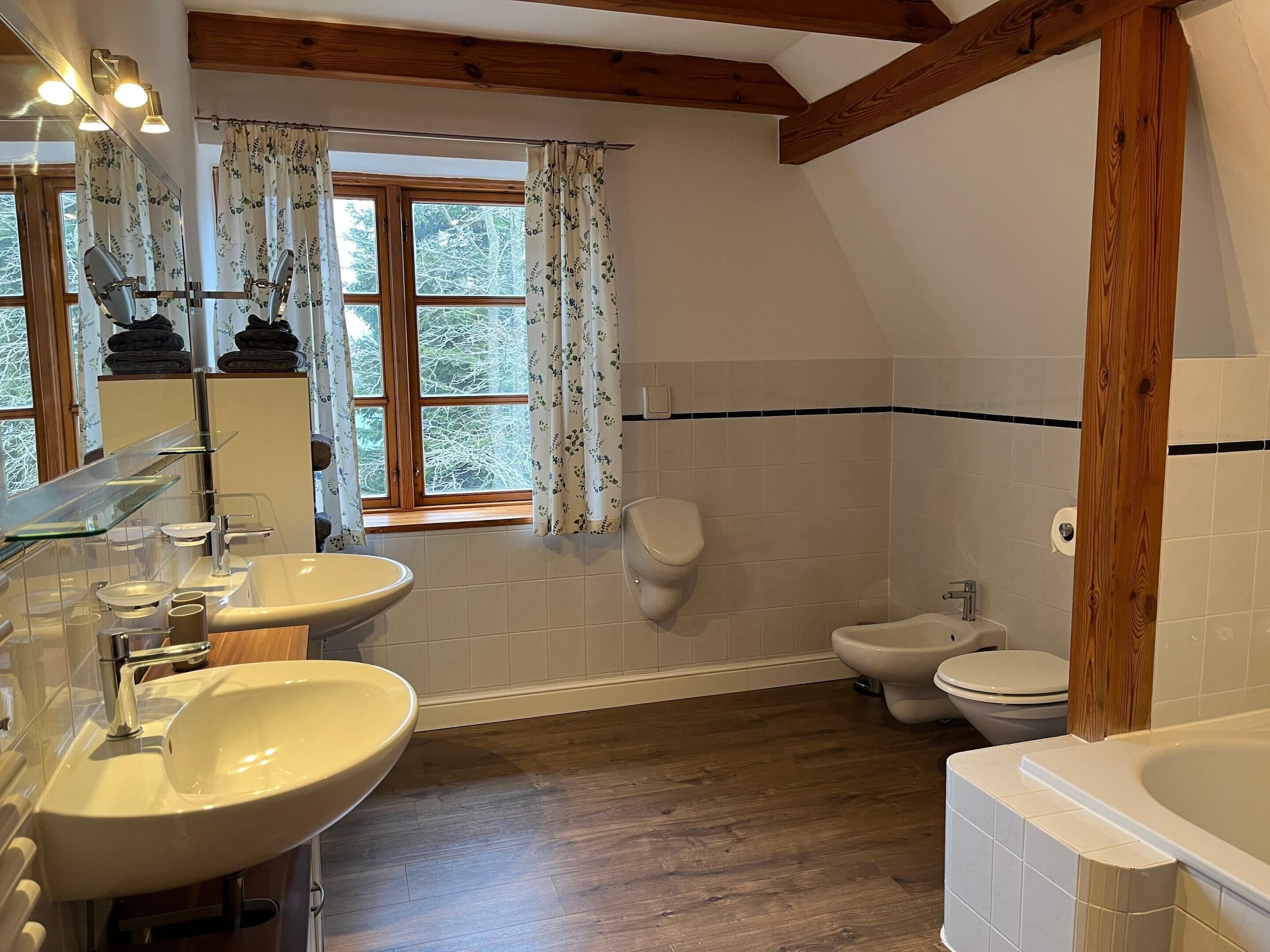 Et badeværelse med to håndvaske, toilet og badekar.