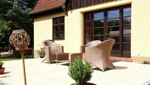 Een terras buiten met rieten meubilair en een bloempot.