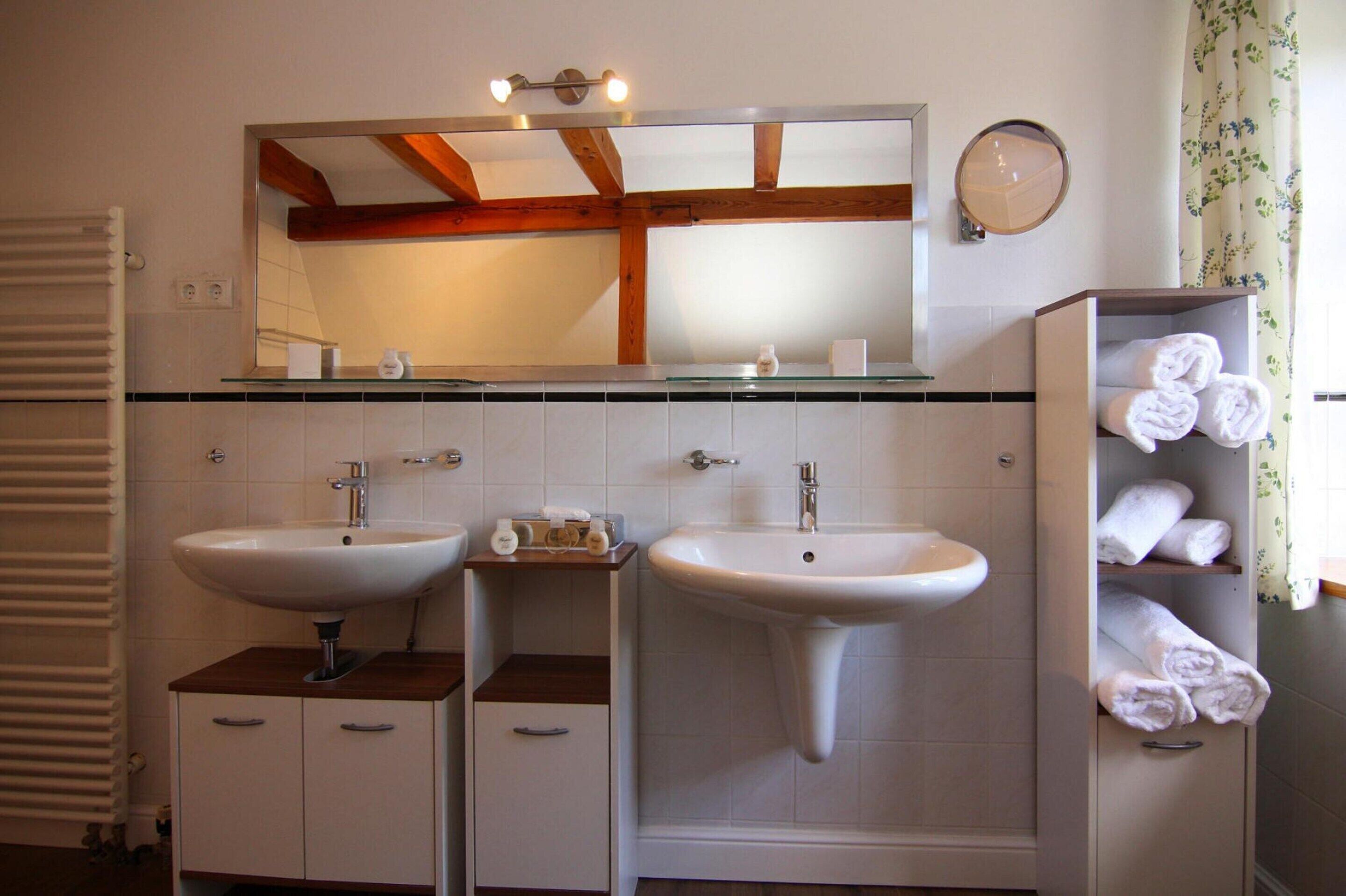 A bathroom with two sinks, a mirror, and a towel rack.