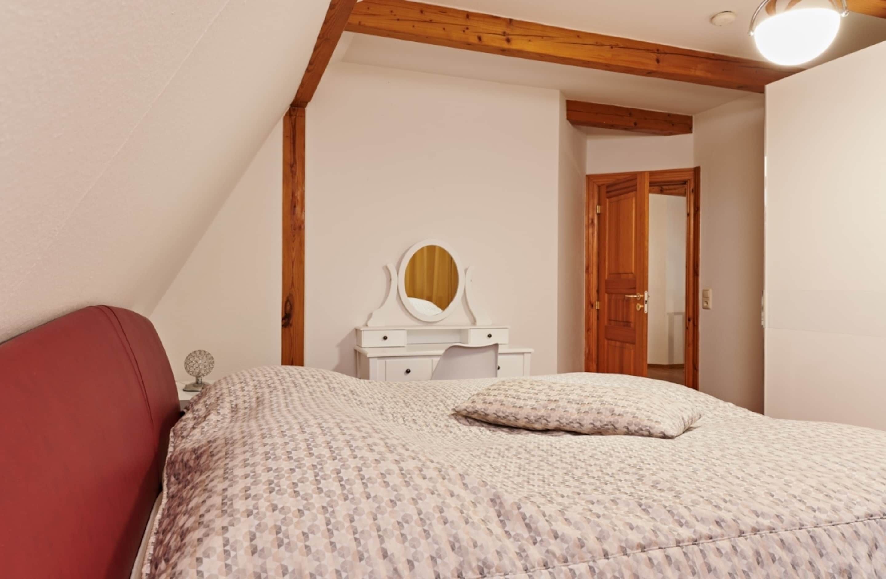 A bedroom with a bed, a dresser, a mirror, and a door.