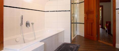 A bathroom with a bathtub, shower, and glass-enclosed shower area.