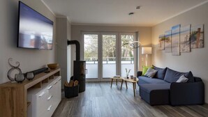 A modern living room with a sofa, a TV, a fireplace, and artwork on the wall. - Exclusives Appartement auf Fehmarn (Fehmarn)