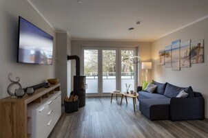Una sala de estar moderna con un sofá, un televisor, una chimenea y obras de arte en la pared.