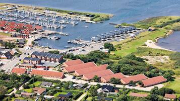 An aerial view of a coastal town with a marina, residential buildings, and green spaces.