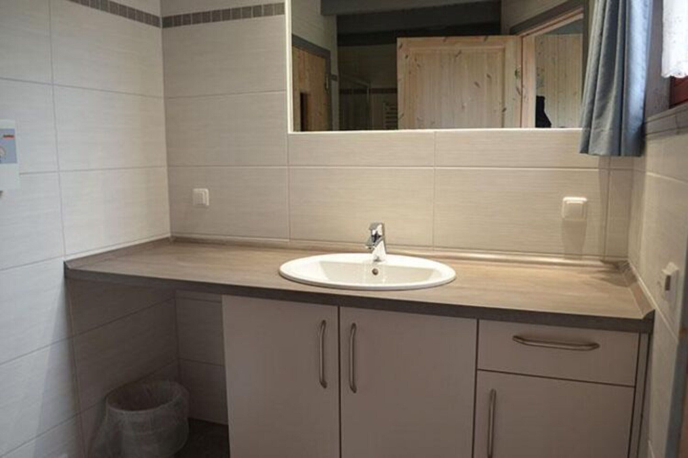 A bathroom with a sink, mirror, and cabinets.