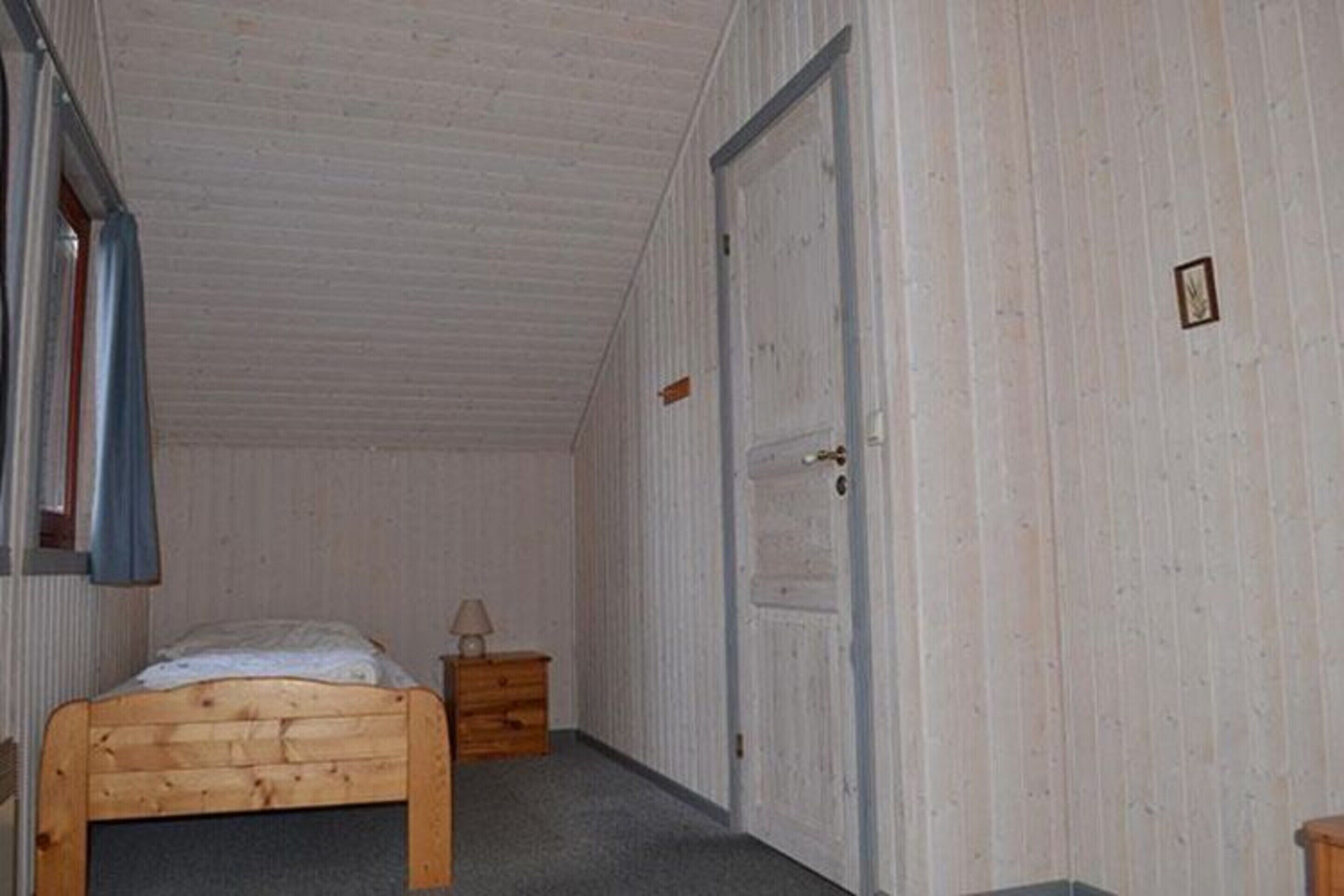 A bedroom with a wooden bed, a dresser, and a door.