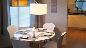 A dining area with a round table, four chairs, and a hanging lamp. - Home Port Holiday Home, Dornum (Dornum)