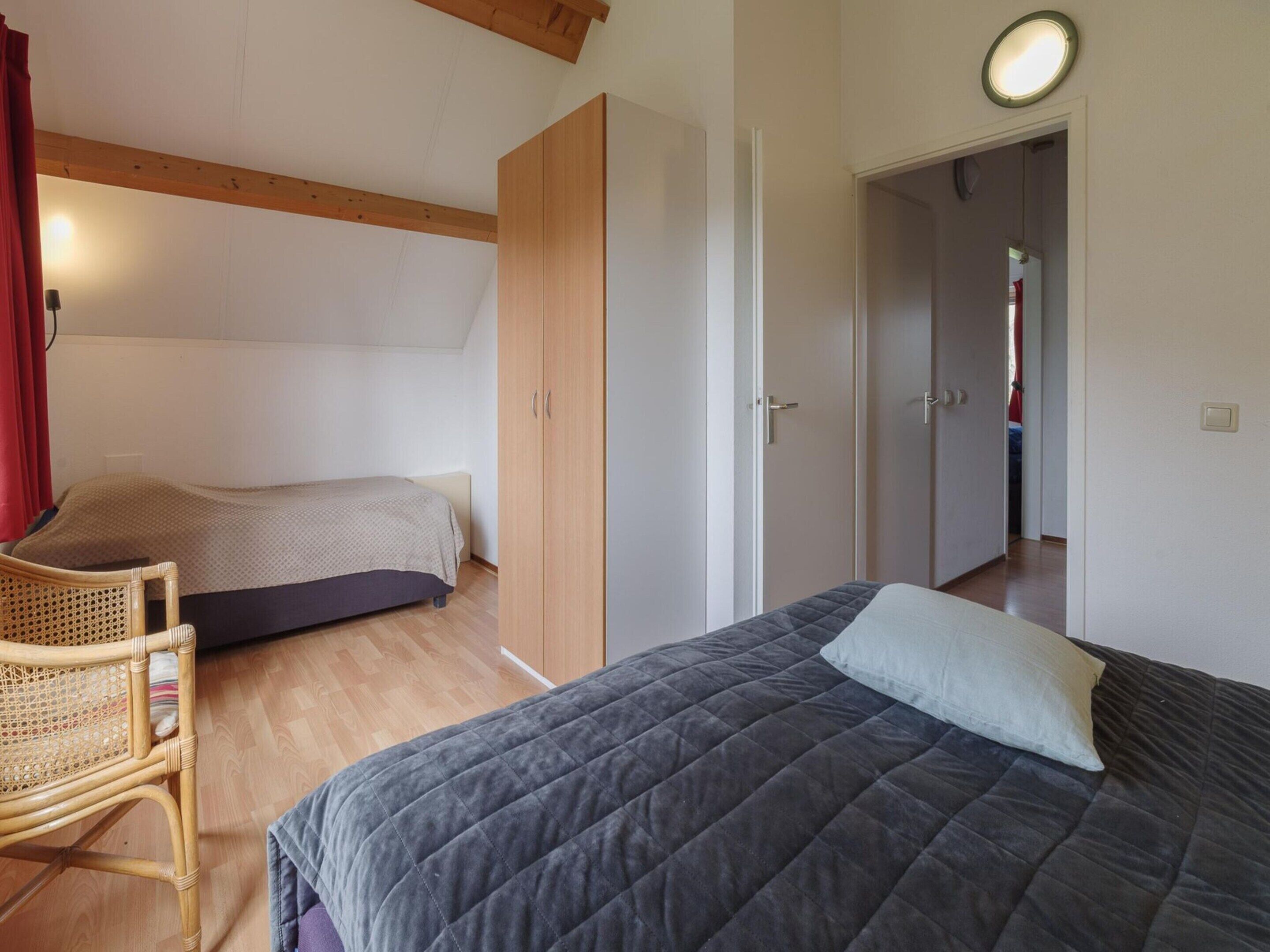 A bedroom with a bed, a chair, and a wardrobe.