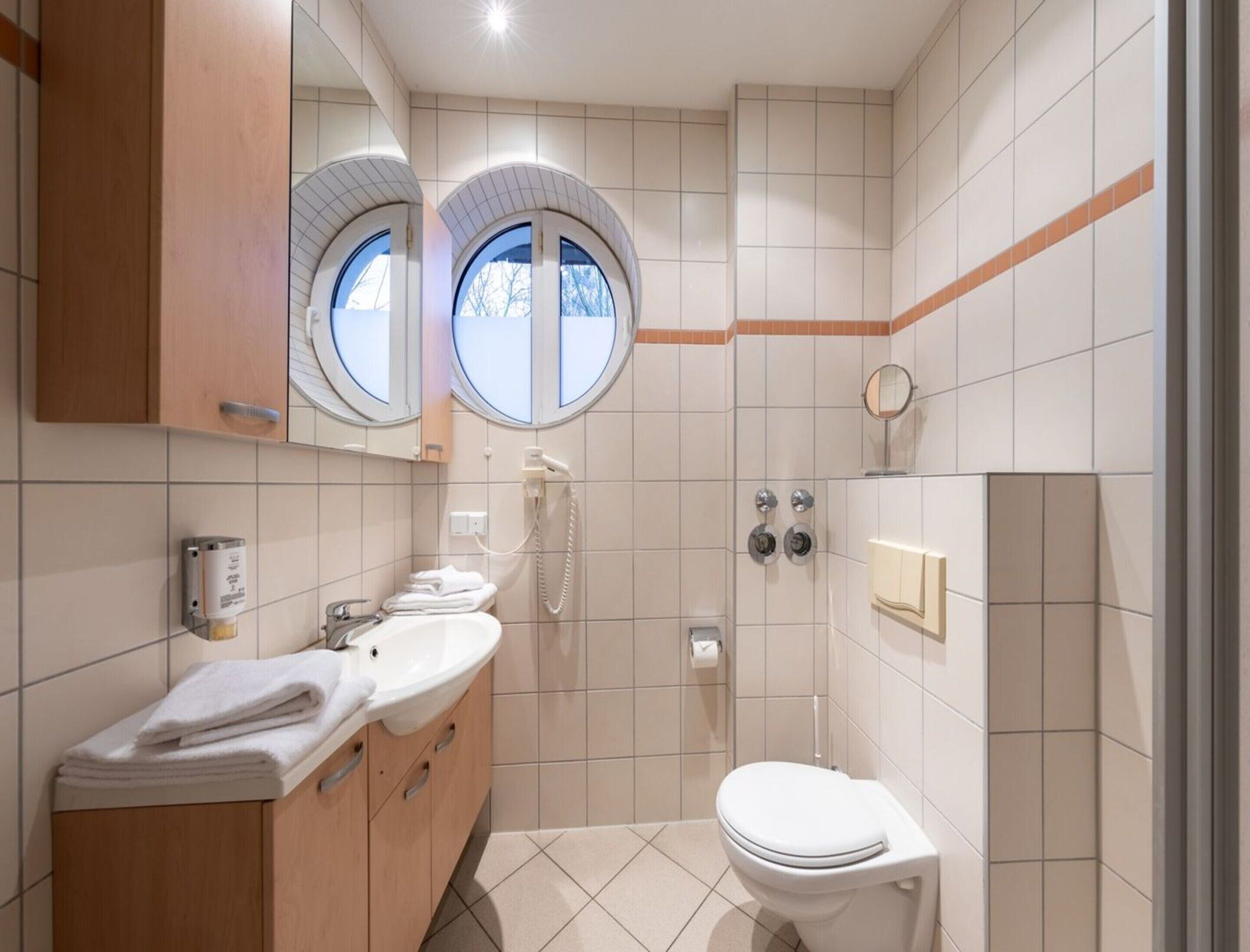 Une salle de bain moderne avec deux lavabos, des toilettes, une douche et un miroir.