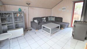 Een woonkamer met een grijze bank, een witte salontafel, een kast met glazen deuren en een radiator.