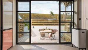 A modern kitchen with a large sliding glass door leading to an outdoor patio. - Birdbank Cottage - Two Bedroom Cottage, Sleeps 4 (St Ives)
