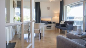 Un salon moderne avec un téléviseur, un canapé et un coin repas.