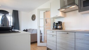 Une cuisine moderne équipée d’un four à micro-ondes encastré, d’une machine à café et d’une table à manger avec un plateau en verre.